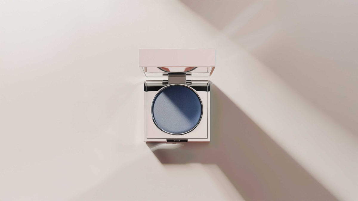 An open compact of cream in raking light on a pale surface