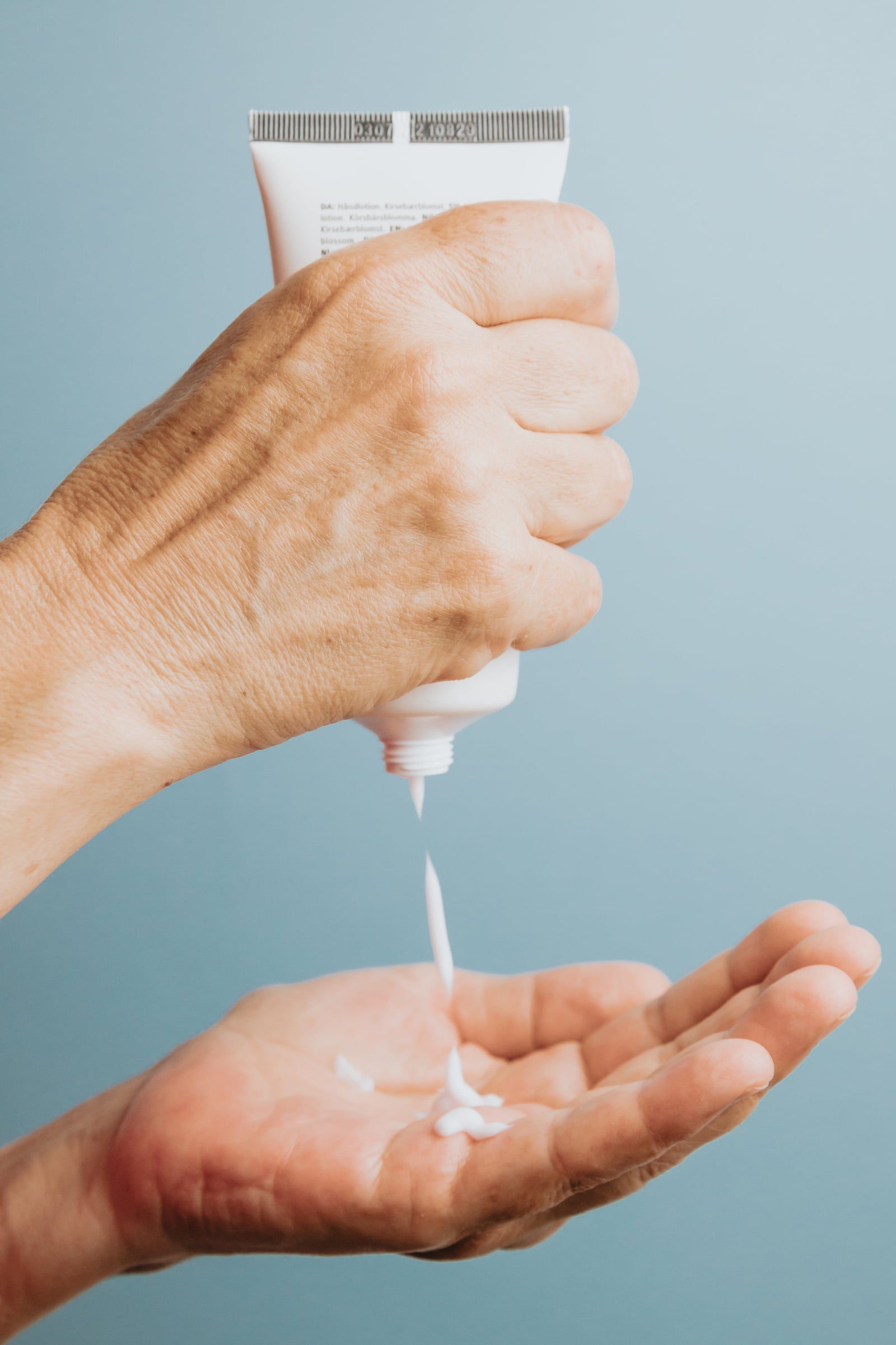 A tube being squeezed into an open palm, showing how much product a full dose is